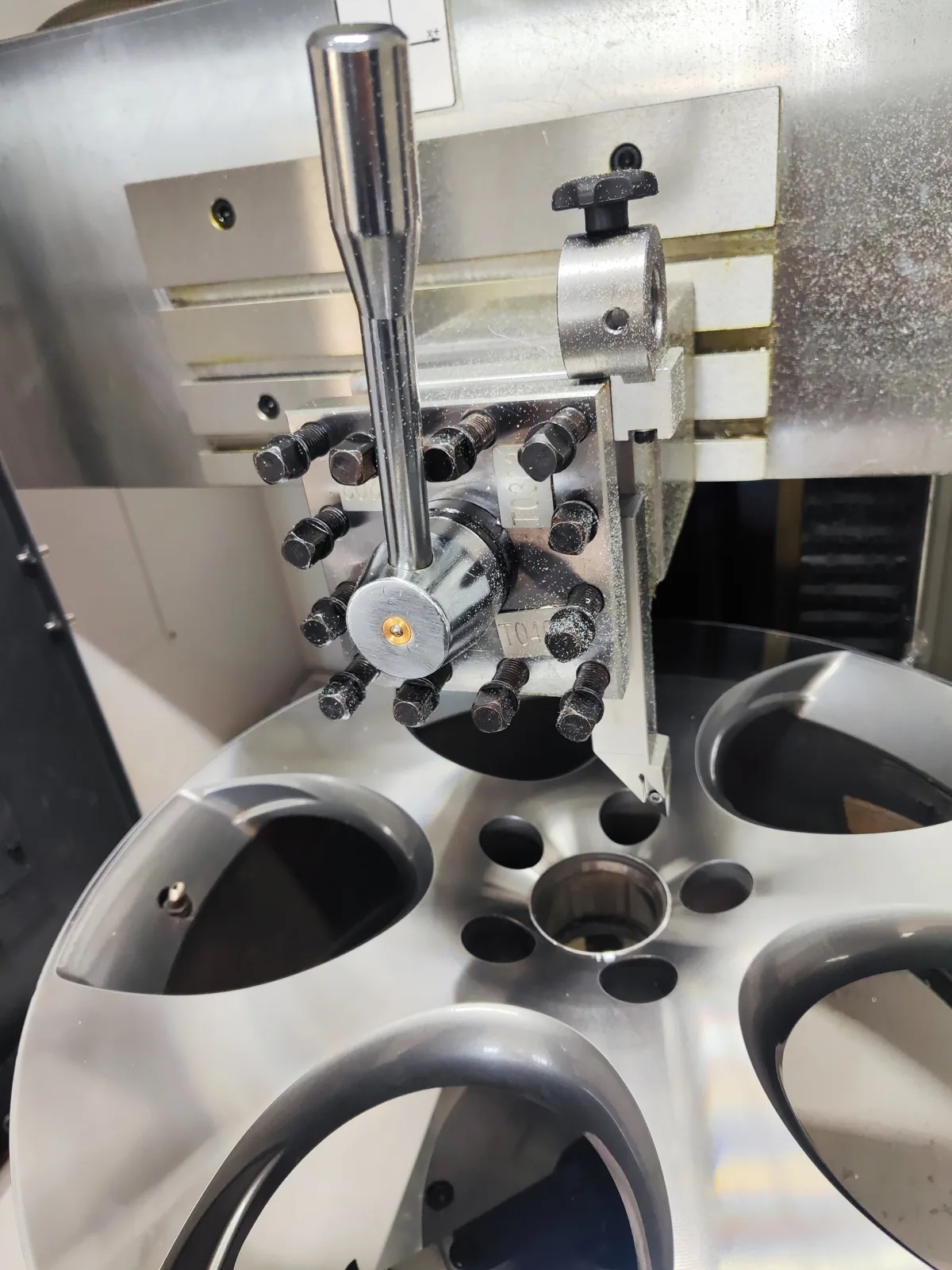 Głowica narzędziowa tokarki CNC nad licem felgi aluminiowej w warsztacie KTJ